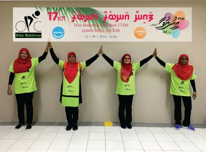 Four riders in hi-vis holding hands under the Laamu Eid ride banner