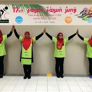 Four riders in hi-vis holding hands under the Laamu Eid ride banner