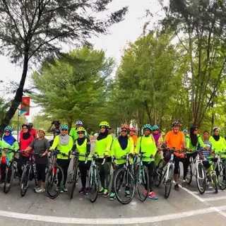 Panoramic view of riders in lime hi-vis on a tree-lined road