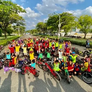 Large group of children and adults stopped on a park road during a ride