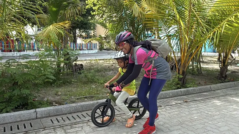 Coach steadying a young rider on a balance bike